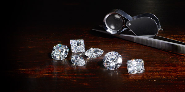Quotazione diamanti usati con lente e pinze su legno